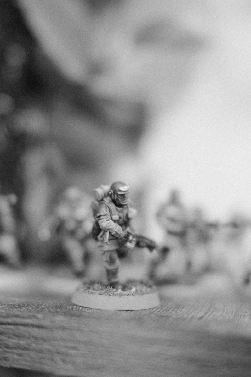 A futuristic soldier miniature holds a rifle on a textured base.